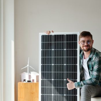 happy Man with Solar Panel Pourquoi installer une centrale photovoltaïque chez-soi ?